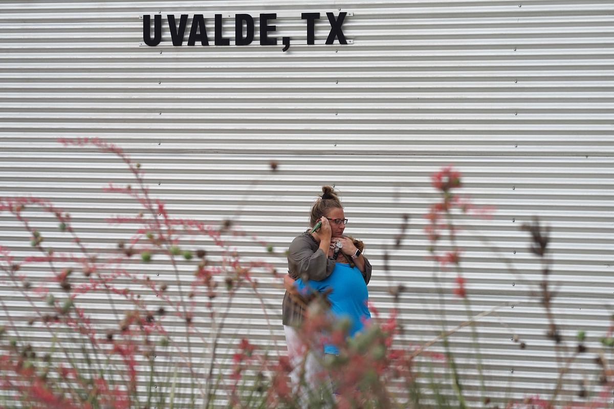 A woman cries and hugs a young girl while on the phone outside the Willie de Leon Civic Center where grief counseling will be offered in Uvalde, Texas. Credit: AFP Photo