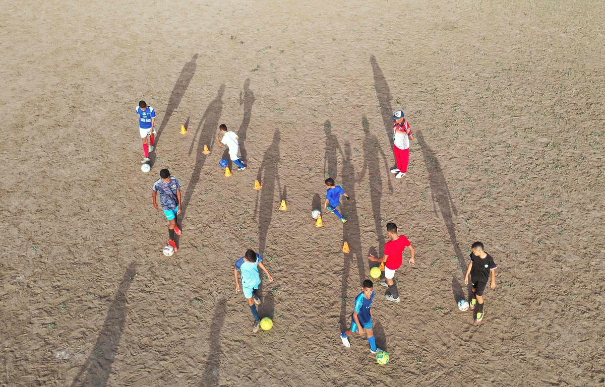 Aerial view of children playing football on a dusty field in Barrancas, Guajira province, Colombia. Credit: AFP Photo