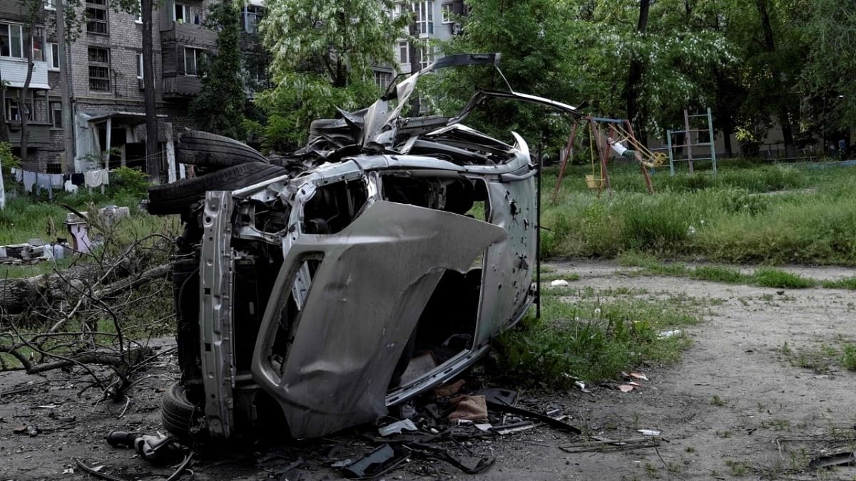 A boy plays on a swing near a destroyed car in a residential area of Mariupol on May 29, 2022, amid the ongoing Russian military action in Ukraine. Credit: AFP Photo