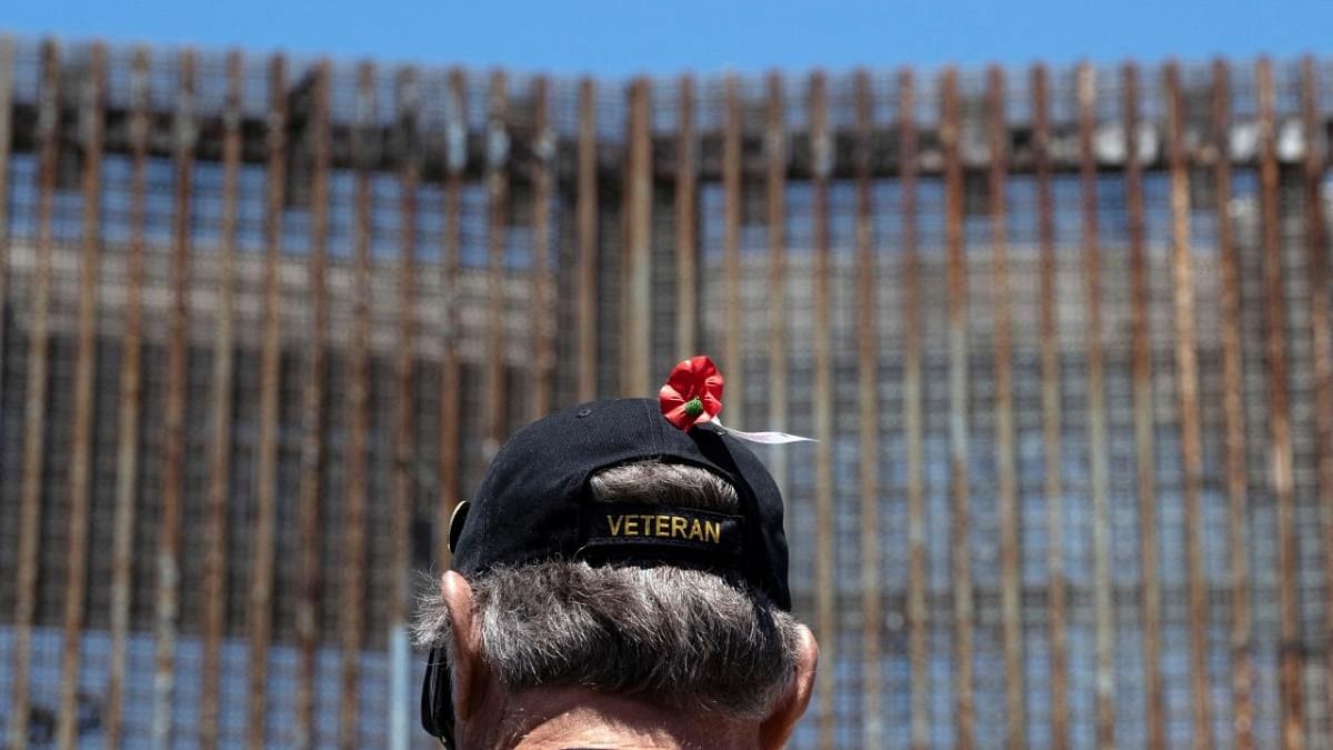 A veteran stands next to the border fence during the