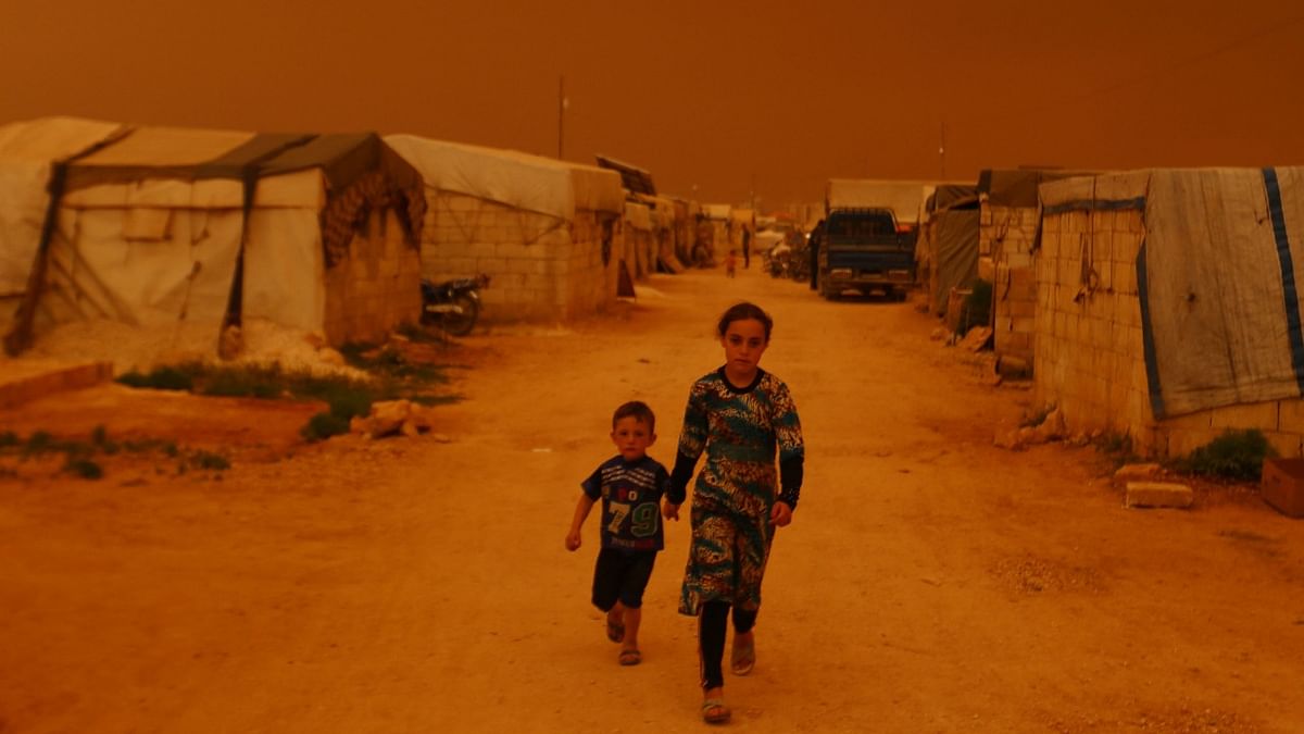 Displaced children walk past tents during a dust storm on the outskirts of the rebel-held town of Dana, in the northwestern Idlib province near the Turkish-Syrian border. Credit: AFP Photo