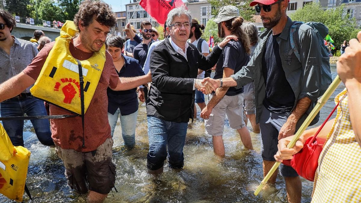 French leftist party La France Insoumise (LFI) leader and Member of Parliament and leader of the left-wing coalition Nouvelle Union Populaire Ecologique et Sociale (NUPES) Jean-Luc Melenchon (C) shakes hands with supporters as he crosses the Clain river near the Joubert bridge as part of a campaign visit in Poitiers, western France. Credit: AFP Photo