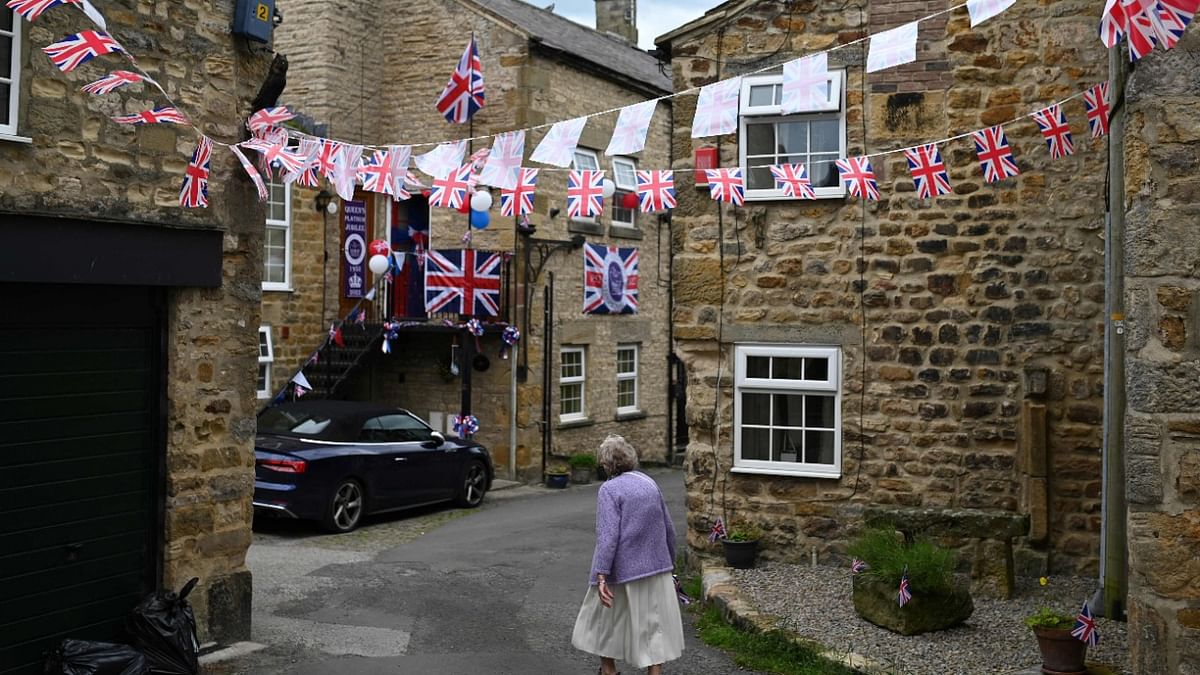 A woman has a wlak in the decorated streets of Masham, northern England, on June 3, 2022 during Queen Elizabeth II's platinum jubilee celebrations. Credit: AFP Photo