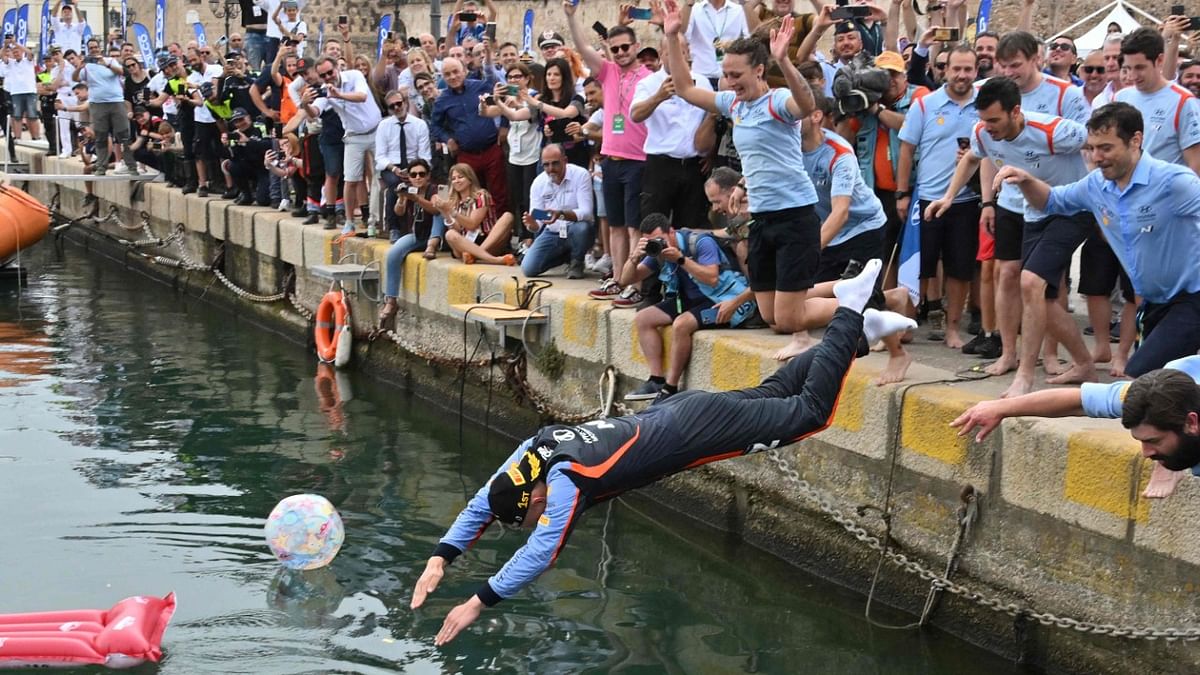 Race winner Estonian driver Ott Tanak (C) and his team members dive in the port on June 5, 2022 in Alghero, celebrating after the Rally of Sardegna, 5th round of the FIA World Rally Championship. Credit: AFP Photo