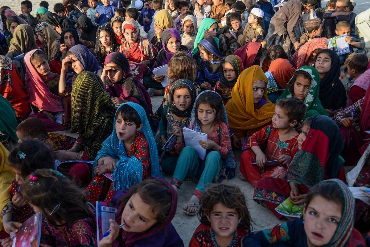 Afghan children attend a class on a mobile school in Kandahar which is an initiative by volunteers wherein a vehicle carrying all sort of study material travels from village to village conducting classes for the children. Credit: AFP Photo