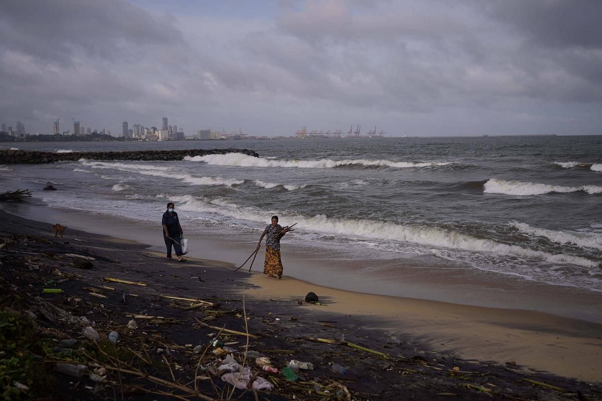 Women collect timber washed ashore to be used as firewood amid cooking gas shortage in Colombo, Sri Lanka. Credit: AP Photo