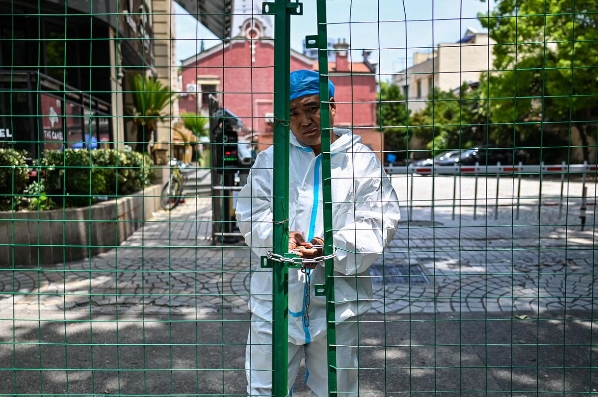 A worker padlocks fencing securing a residential area under Covid-19 lockdown in the Xuhui district of Shanghai. Credit: AFP Photo