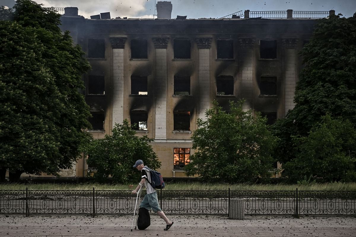 A man walks past a burning college after a strike in Lysychansk, eastern Ukrainian region of Donbas. Credit: AFP Photo