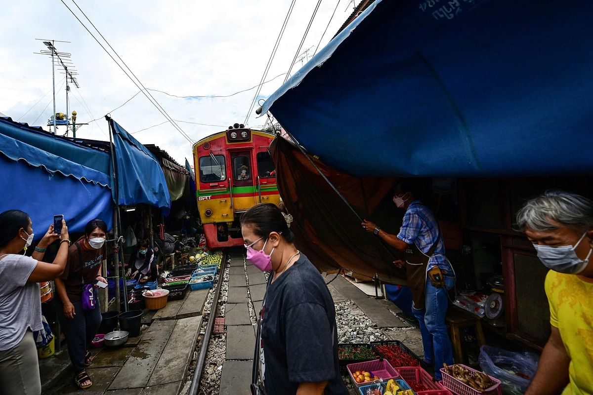 Vendors rushing to open their awnings after a passenger train passed through the Mae Klong railway market in Samut Songkhram province, around 80 kms (50 miles) southwest of Bangkok. Credit: AFP Photo