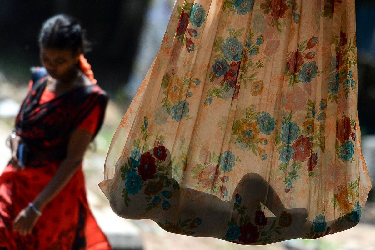A woman walks past as a child sleeping on a makeshift hammock along a street in Chennai. Credit: AFP Photo