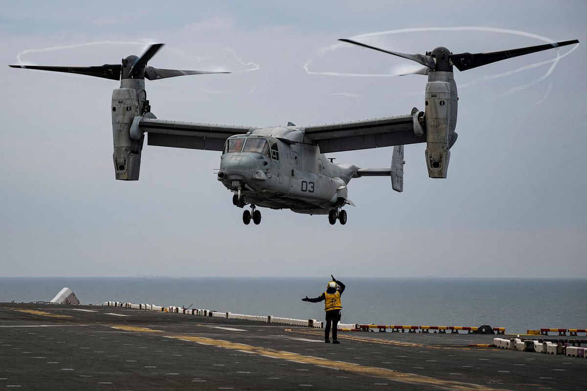 An Aviation Boatswain’s Mate (Bottom) signals to the pilots of the MV-22 Osprey assault support aircraft, assigned to the 22nd Marine Expeditionary Unit. Credit: AFP Photo