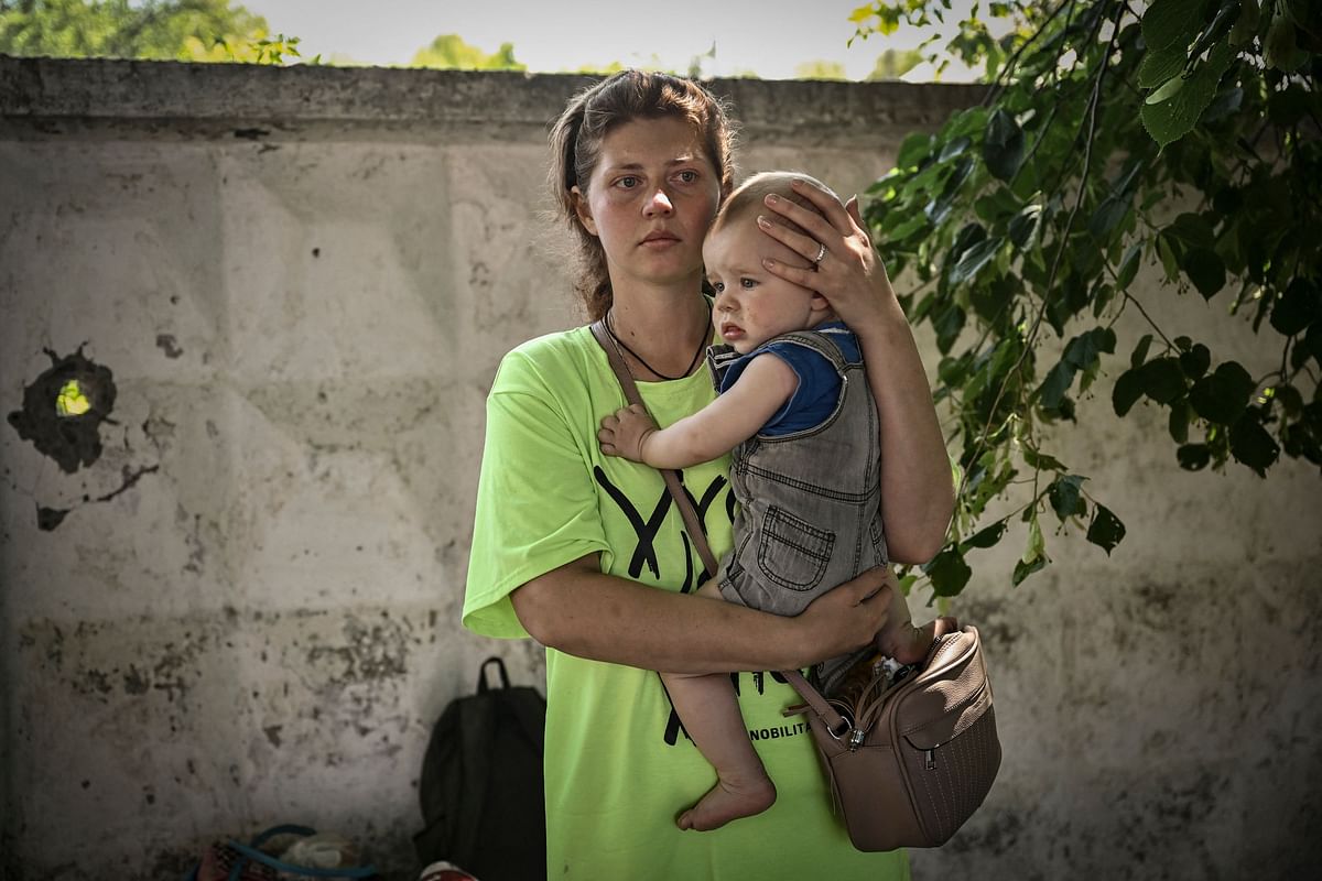 A woman holds her baby as she waits to board a bus and evacuates from the city of Lysychansk in the eastern Ukraine region of Donbas. Credit: AFP Photo