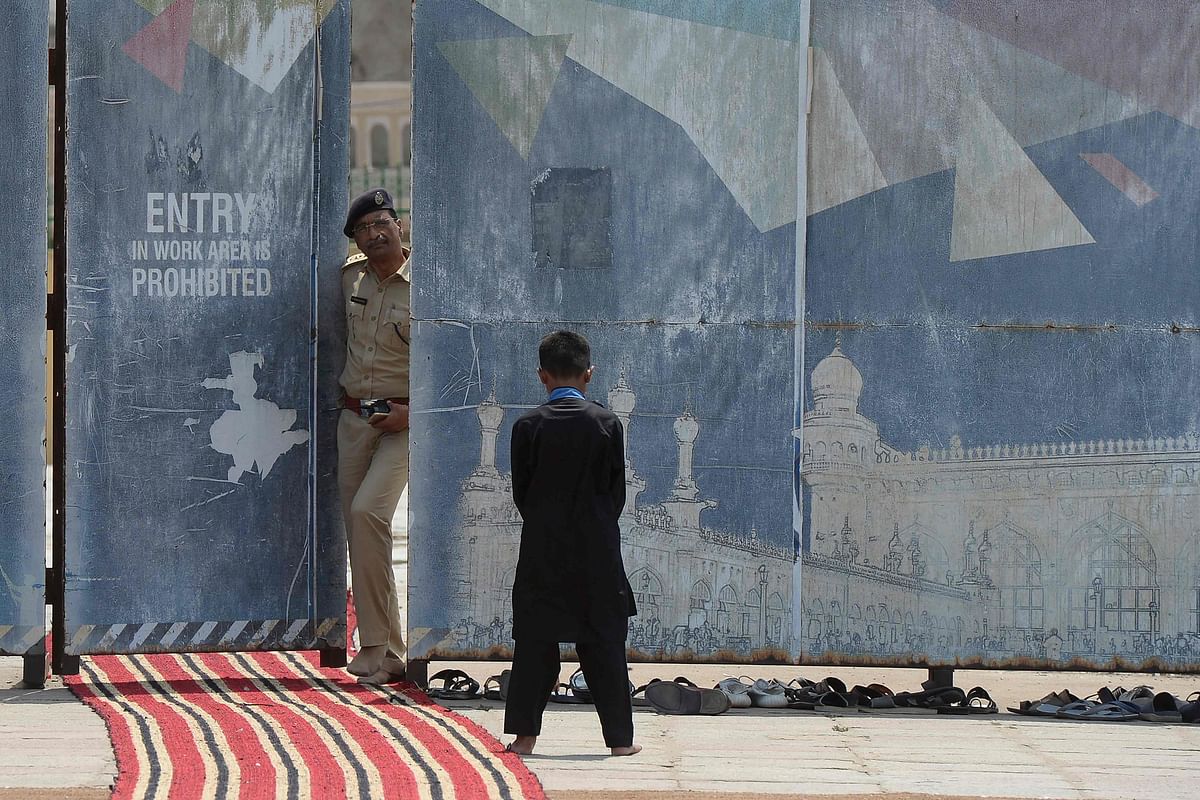 A police officer looks on as an Muslim boy offers Friday prayers at the Mecca Masjid in Hyderabad. Credit: AFP Photo