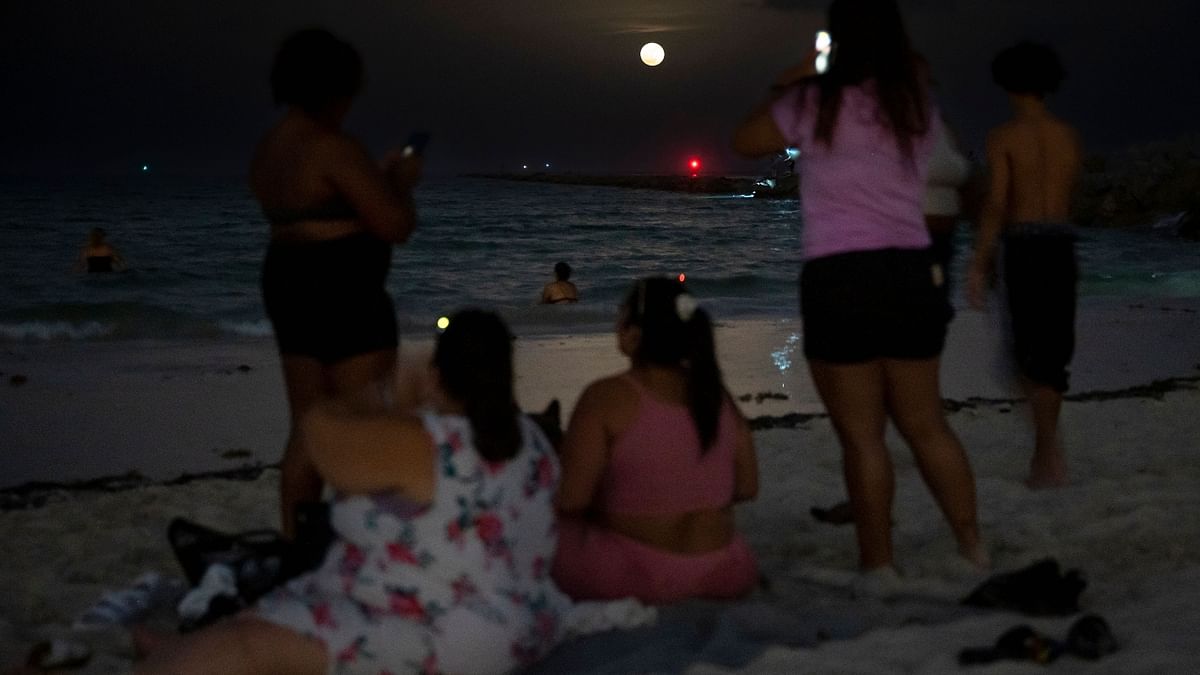 People gather to watch a full moon, the 'Strawberry supermoon', in Miami Beach, Florida. Credit: AFP Photo