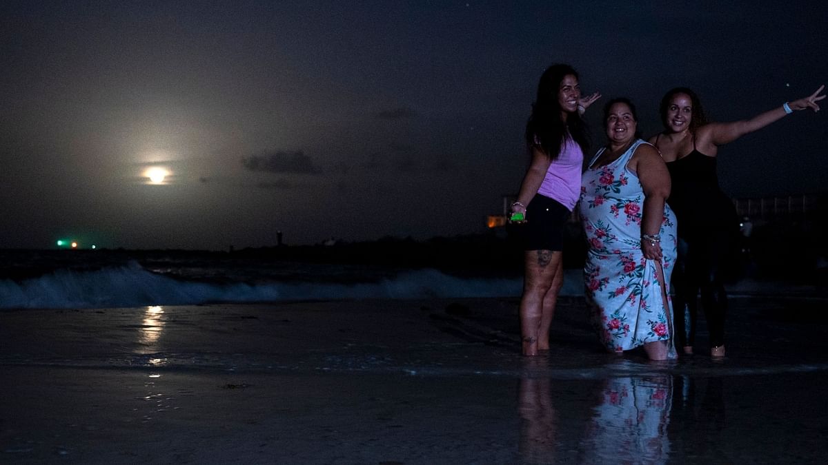 People pose for a picture as they gather to watch a full moon, the 'Strawberry supermoon', as it rises in Miami Beach, Florida. Credit: AFP Photo