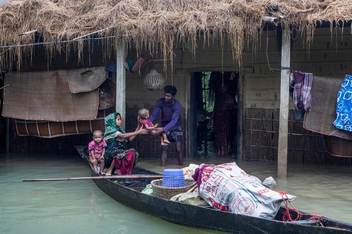 A woman holds her child as they evacuate their house submerged in a flooded area following heavy monsoon rainfalls in Goyainghat, Bangladesh. Credit: AFP Photo