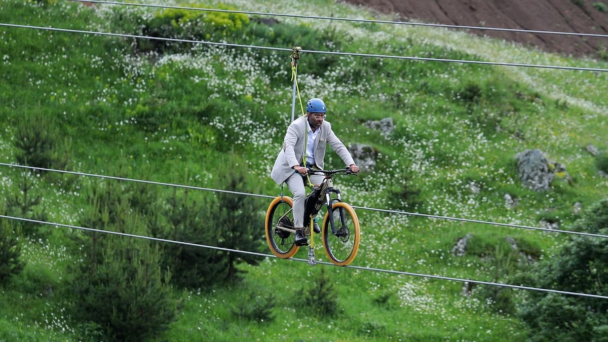 A man rides a bike on a zip line during the opening ceremony of the glass bridge over Dashbashi Canyon outside the town of Tsalka, Georgia. Credit: Reuters Photo