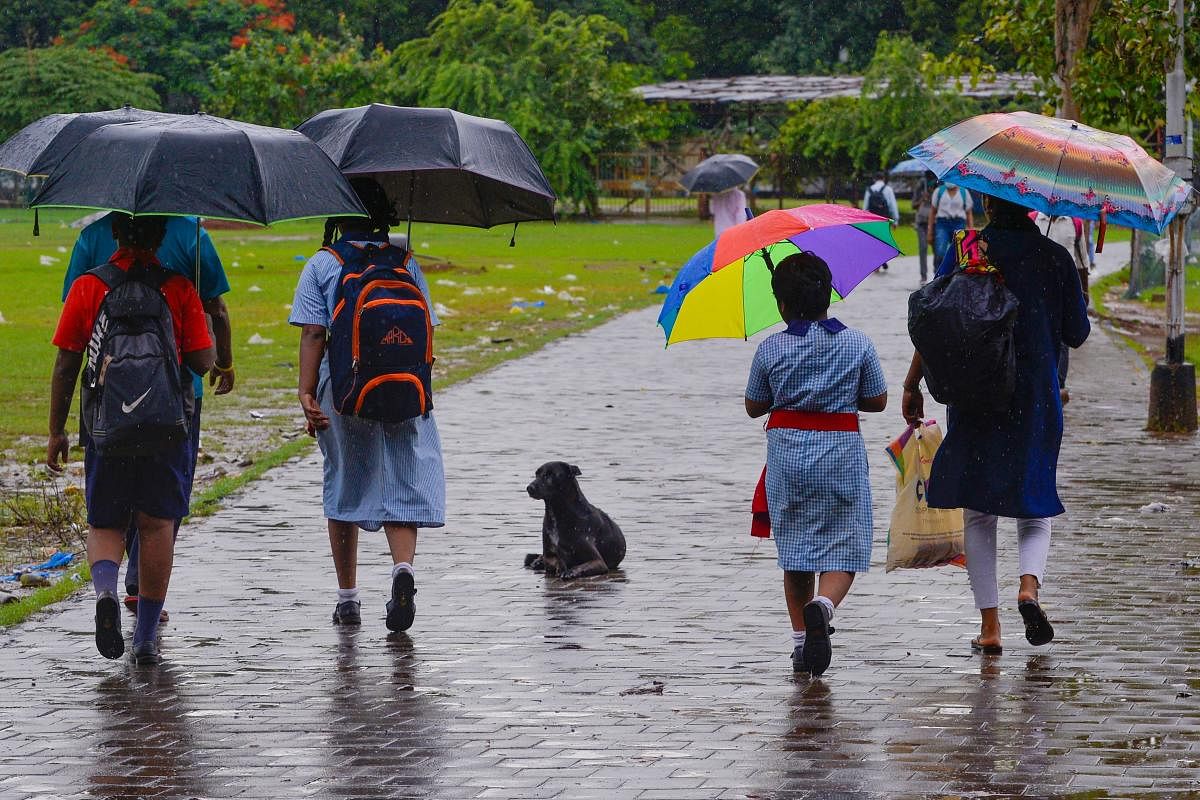 Guardians walk children to school amidst rain in Mumbai. Credit: AFP Photo