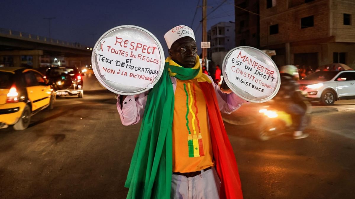 Ibrahima Soumare, 47, a supporter of Senegal's main opposition coalition Yewwi Askan Wi holds signs glued on pot lids during a protest over the disqualification of their national list for the July 31 legislative election in Dakar. Credit: Reuters photo
