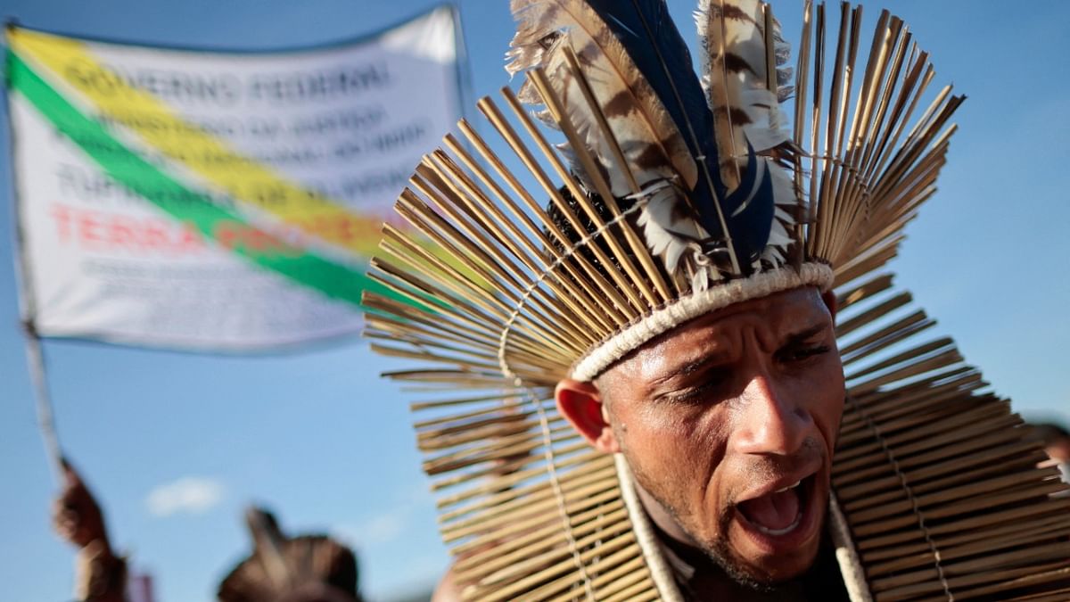 An indigenous man takes part in a protest against Brazilian President Jair Bolsonaro's government, Brazil's National Indian Foundation (FUNAI)'s President Marcelo Augusto Xavier da Silva, to ask the Supreme Court to define the demarcation of Indigenous lands and to demand justice for journalist Dom Phillips and indigenous expert Bruno Pereira, who were murdered in the Amazon, in Brasilia, Brazil. Credit: Reuters photo