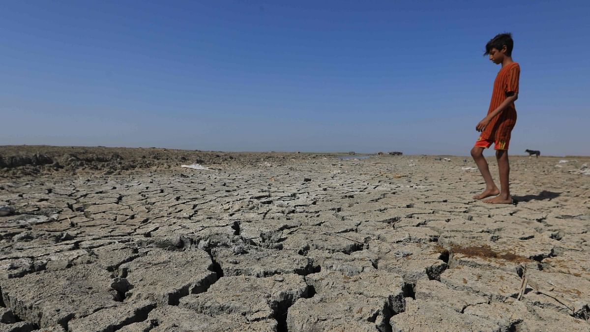A boy walks on the dried-up bed of a section of Iraq's southern marshes of Chibayish in Dhi Qar province, as water levels recede due to drought, on June 28, 2022. - Iraq's drought reflects a decline in the level of waterways due to the lack of rain and lower flows from upstream neighboring countries Iran and Turkey. Credit: AFP Photo