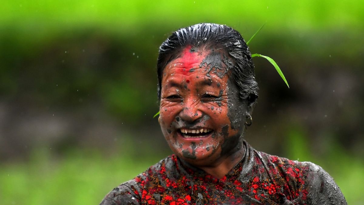 A mud-covered farmer smiles in a rice paddy field during