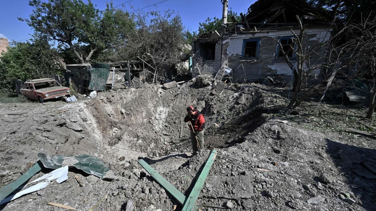 A worker stands in a crater in front of a heavily damaged house in a residential area of Kramatorsk on July 4, 2022, the day after a Russian rocket attack. Credit: AFP Photo