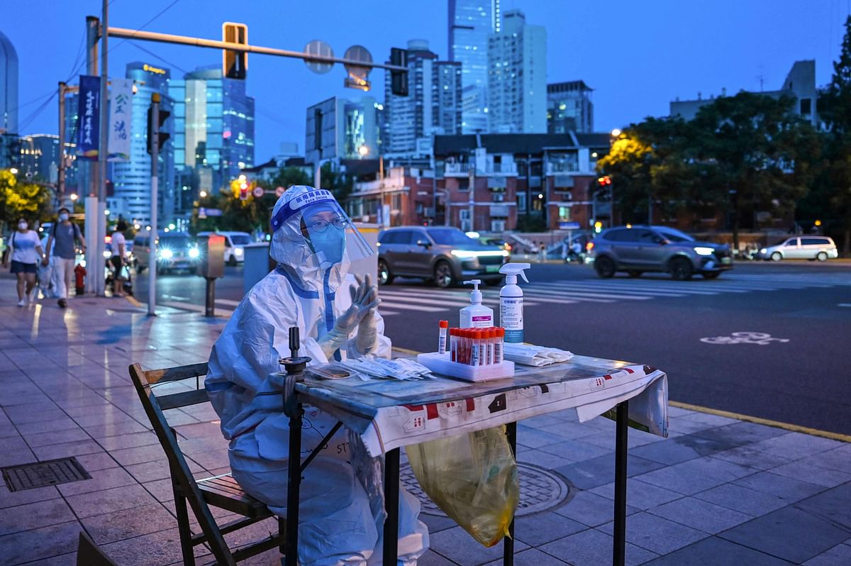 A health worker waits to test people for the Covid-19 coronavirus on a street next to a residential area in the Jing'an district of Shanghai. Credit: AFP Photo