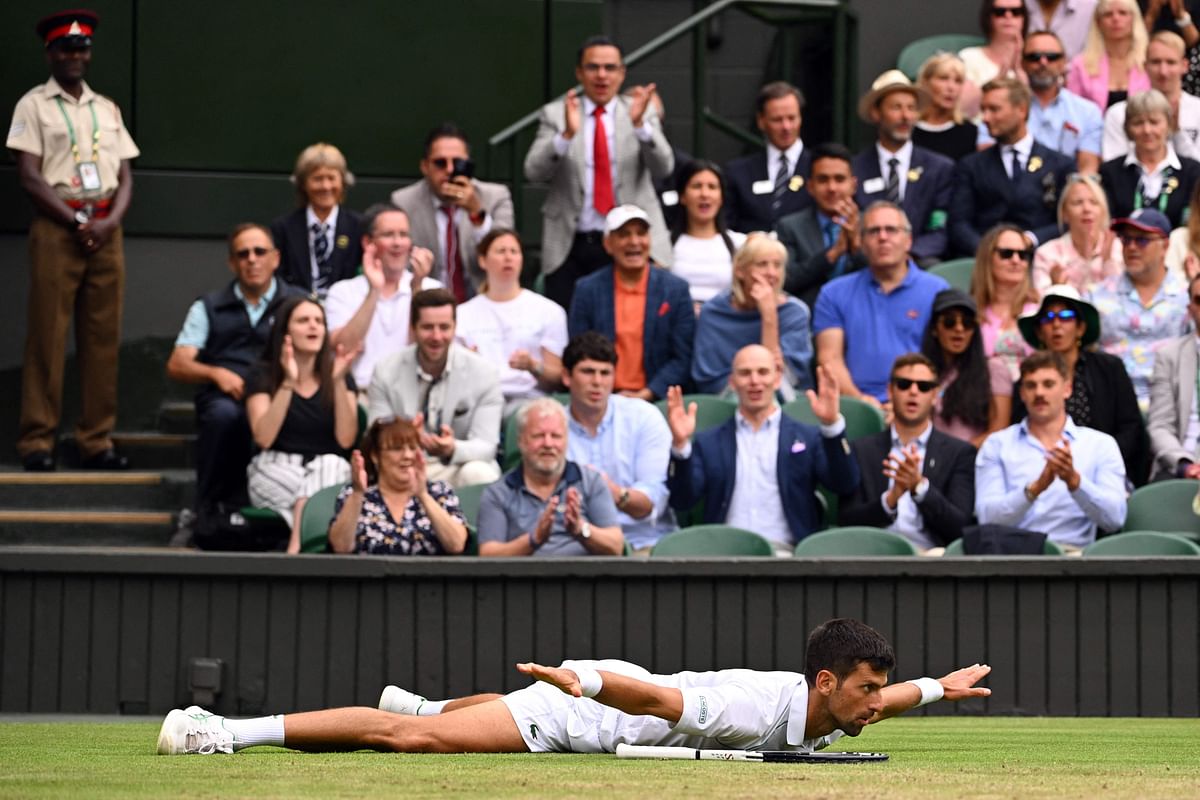 Novak Djokovic reacts as he lies on the lawn during his men's singles quarter final tennis match against Italy's Jannik Sinner on the ninth day of the 2022 Wimbledon Championships at The All England Tennis Club in Wimbledon. Credit: AFP Photo