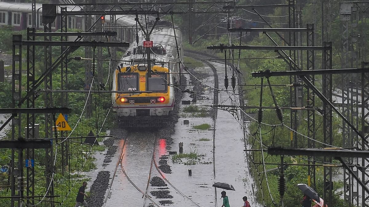 A local train runs on flooded tracks following heavy monsoon rains, in Mumbai. The local train services, considered the lifeline of Mumbai, were affected mainly on the main and harbour corridors of the Central Railway due to waterlogging on tracks near Kurla, slowing down the trains. Credit: PTI Photo
