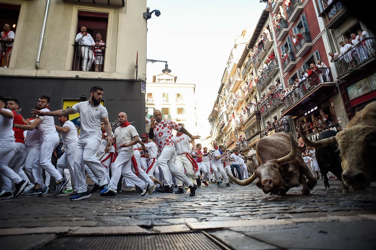 Participants run ahead of bulls during the
