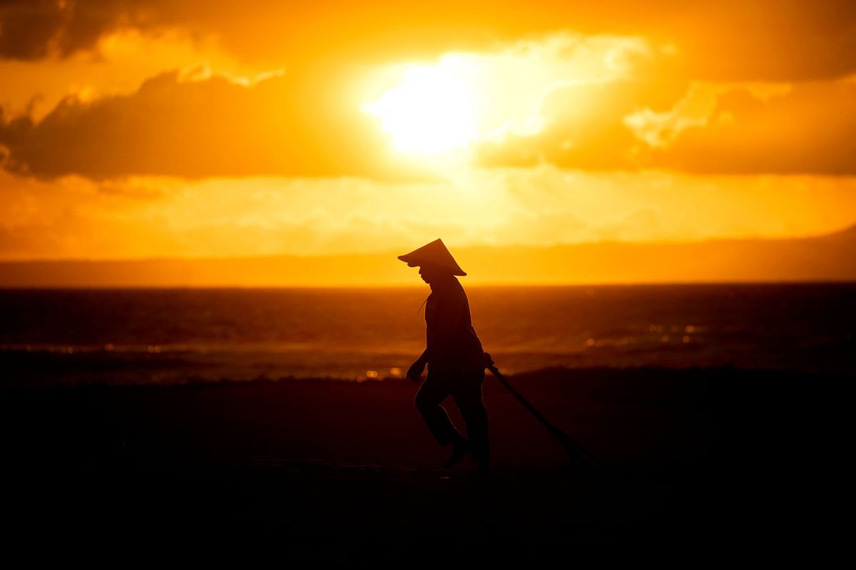 A worker cleans the beach at sunrise in Nusa Dua on the Indonesian resort island of Bali. Credit: AFP Photo