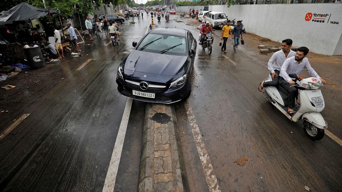 A car is stuck on a road divider after it was washed away by flooding following heavy rains in Ahmedabad. Credit: Reuters Photo