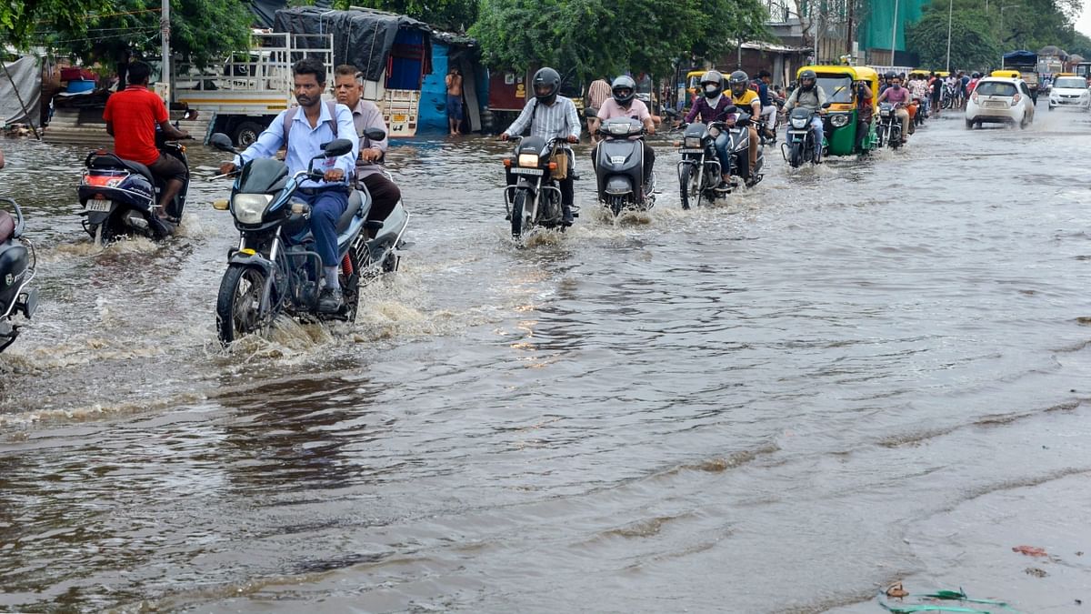 Commuters wade through a waterlogged street after heavy rain in Ahmedabad. Credit: AFP Photo