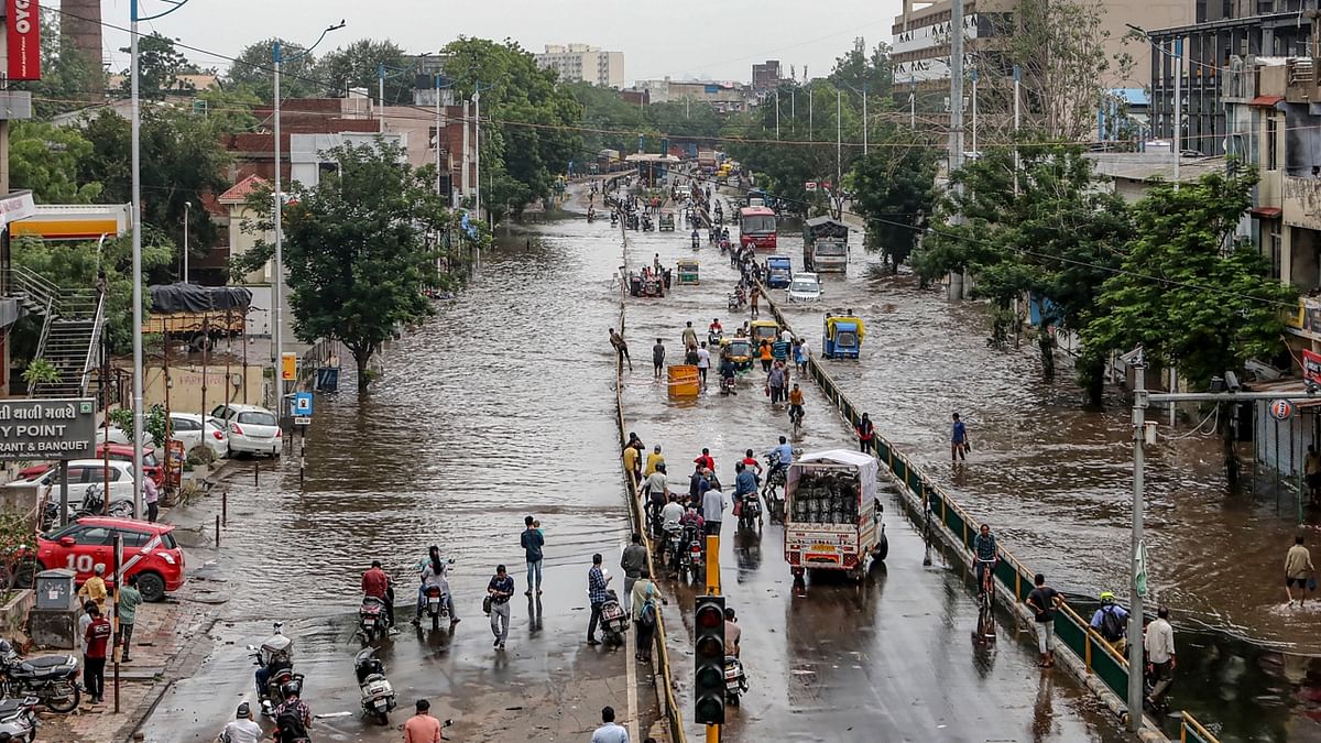 Commuters wade through a waterlogged road after heavy rain in Ahmedabad. Credit: PTI Photo