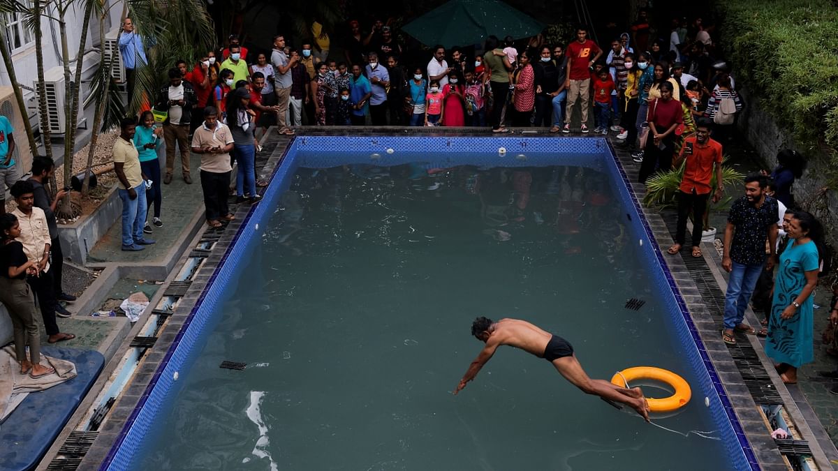 A man jumps into the Sri Lanka Presidential palace's pool as other protestors look on. Credit: Reuters Photo