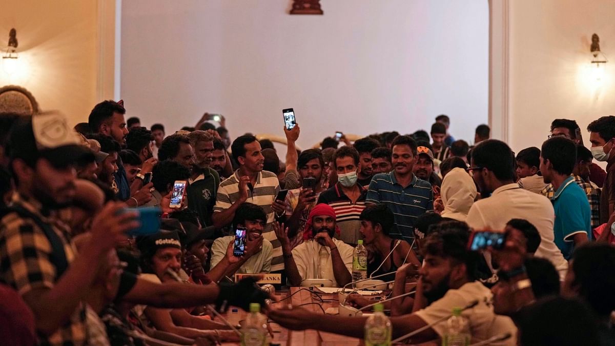 Protesters pretend to hold a cabinet meeting after occupying seats at the cabinet meeting hall of the president's official residence a day after it was stormed in Colombo, Sri Lanka. Credit: AP Photo