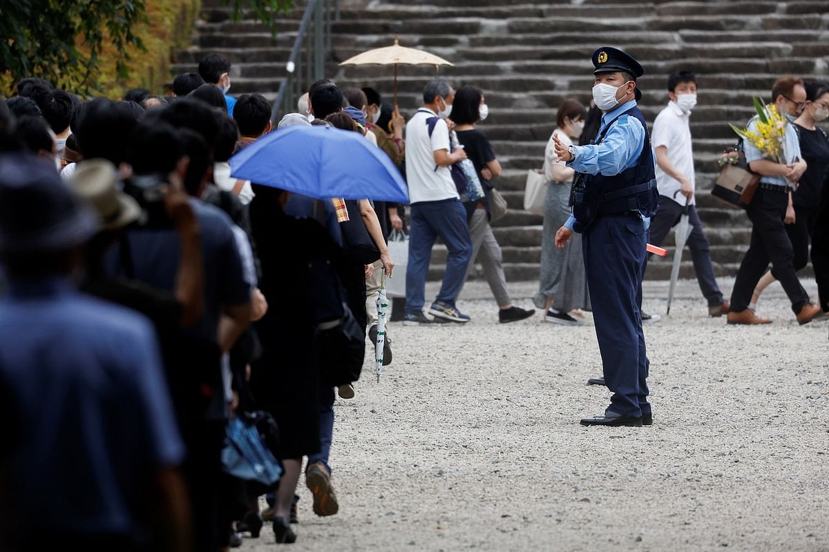 A police officer stands guard as people line up to offer flowers at Zojoji Temple, where the funeral of the late former Japanese Prime Minister Shinzo Abe. Credit: Reuters Photo