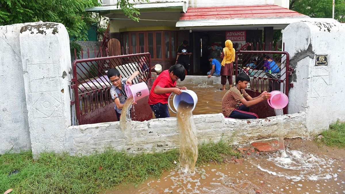 Ahmedabad: Boys pour out rain water from their partially submerged house after heavy rains. Credit: AFP Photo