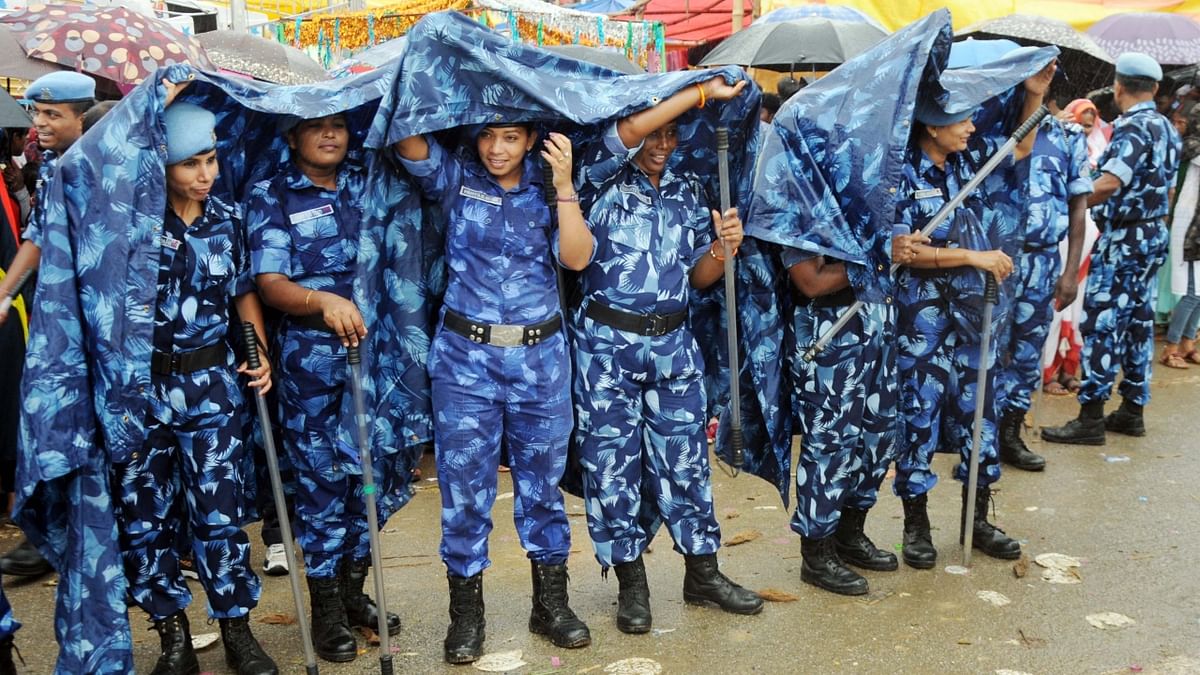 Ranchi: Security personnel use raincoats to take shelter from monsoon rains. Credit: PTI Photo