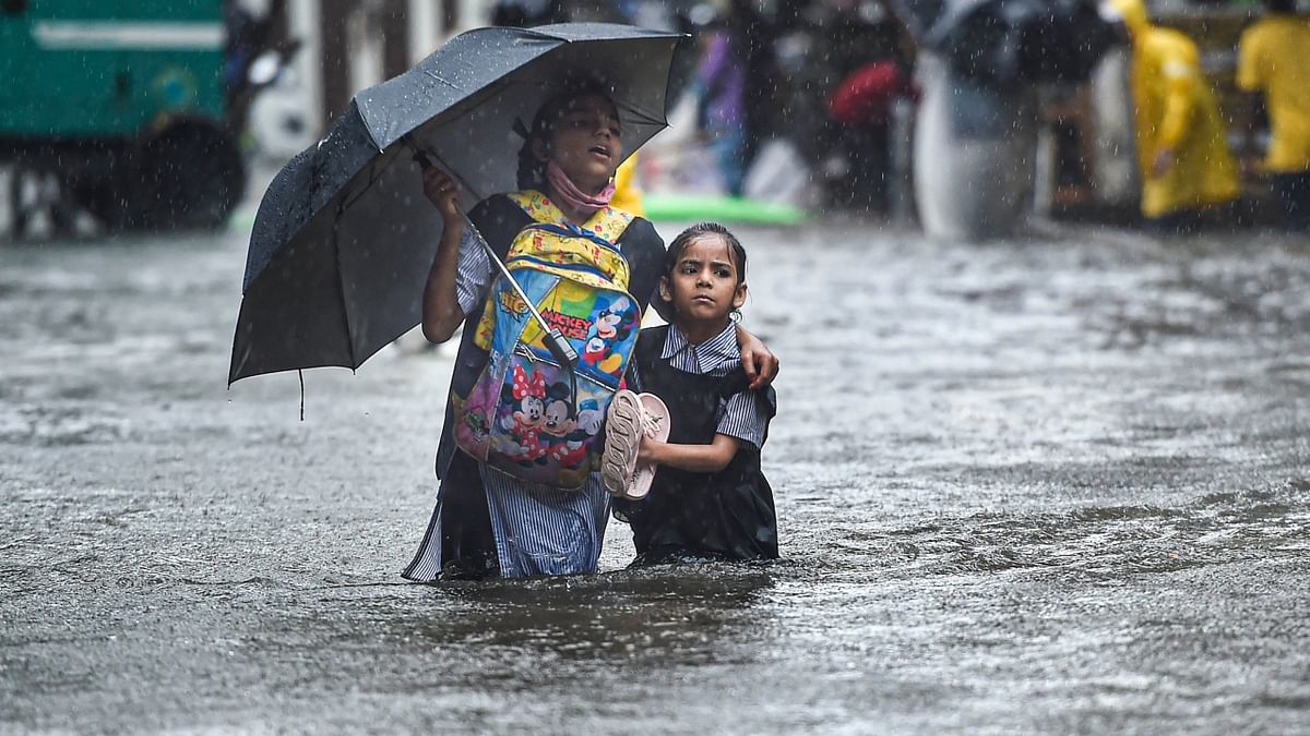 Mumbai: School girls wade through a flooded street following heavy monsoon rains. Credit: PTI Photo