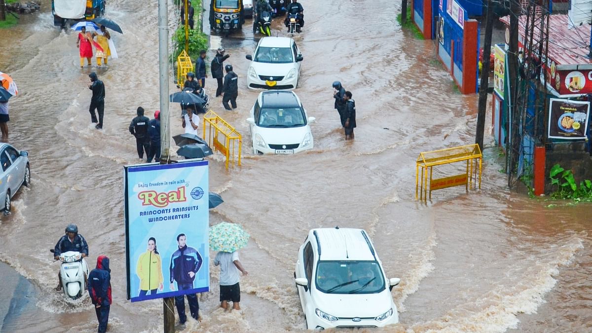 Mangaluru: Vehicles and pedestrians wade through a waterlogged road during monsoon rainfall. Credit: PTI Photo