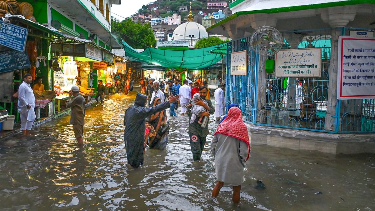 Ajmer: People wade through a waterlogged street near Ajmer Sharif Dargah after heavy rain. Credit: PTI Photo