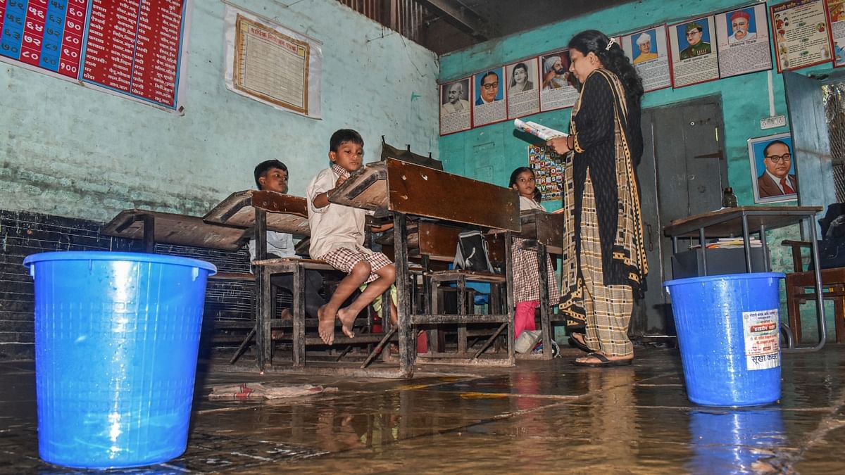 Solapur, Maharashtra: Buckets kept under a school's leaking roof due to incessant monsoon rains as a teacher conducts a class, in Solapur. Credit: PTI Photo