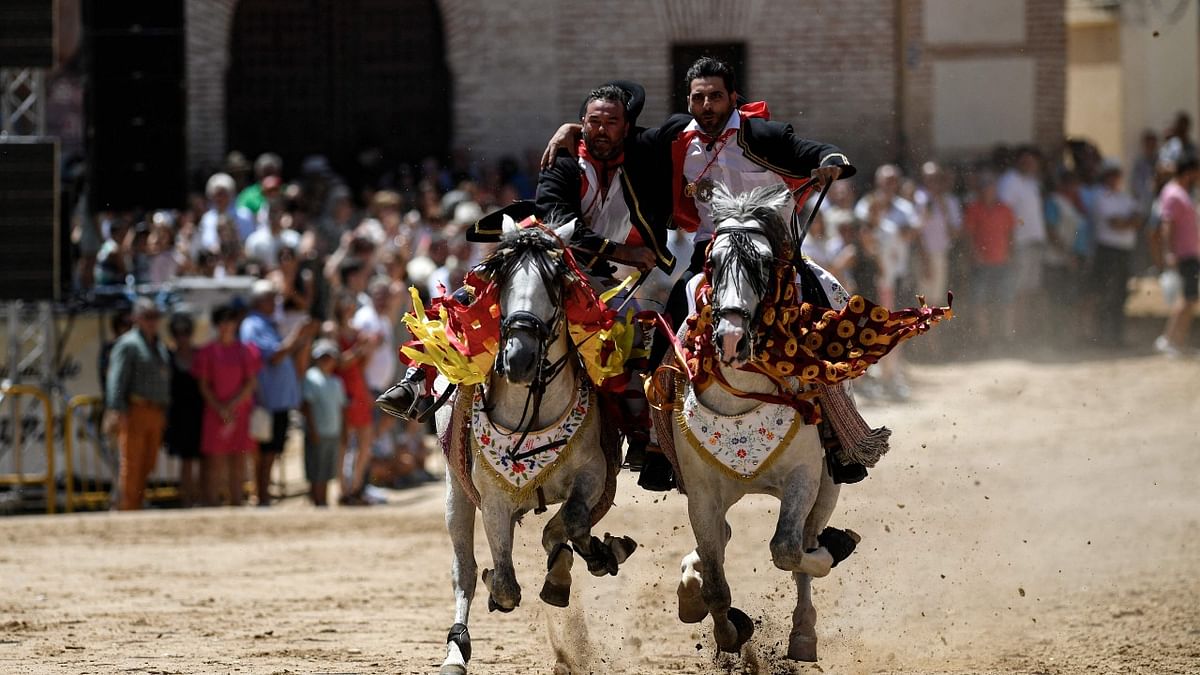 Galloping horse riders clasp one another during the St. James Festival in the village of El Carpio de Tajo, Toledo, Spain. Credit: AFP photo