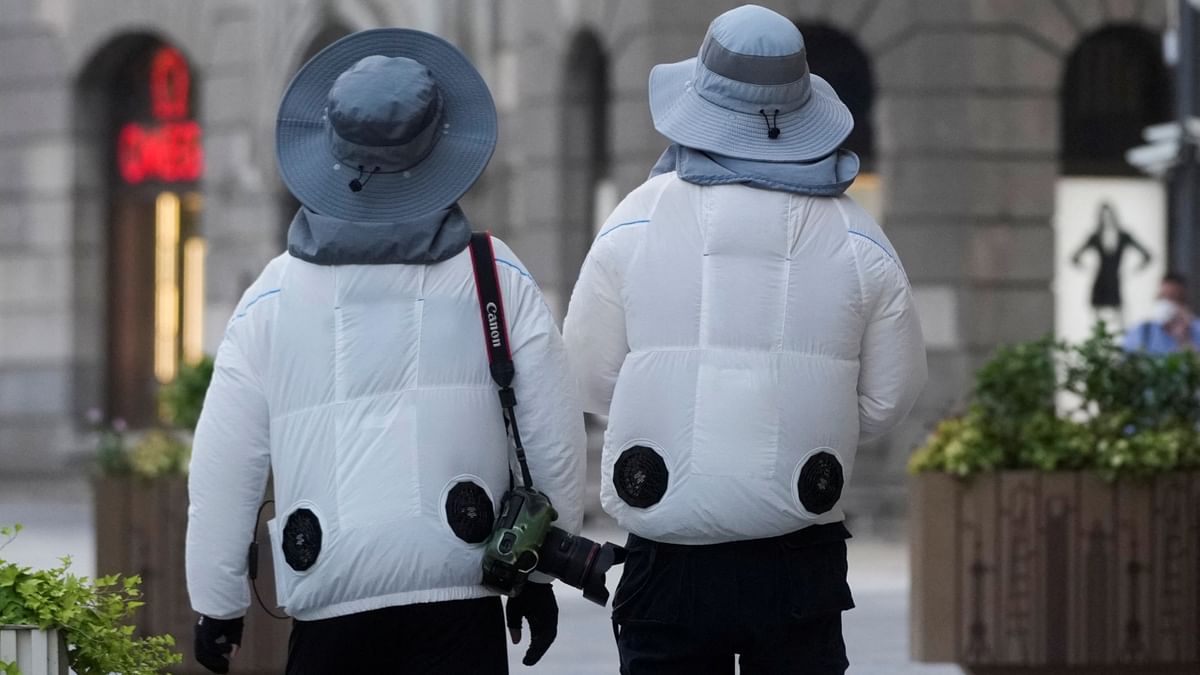 People are seen wearing clothing with cooling fans on a street, amid a heatwave warning in Shanghai, China. Credit: Reuters Photo