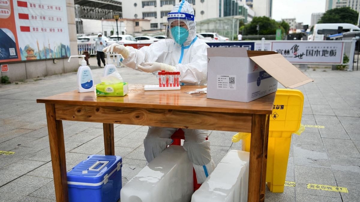 A medical worker wearing a protective suit sits with ice blocks at a nucleic acid testing site during preparations to test residents for the coronavirus disease (COVID-19), amid a heatwave warning in Nanchang, Jiangxi province, China. Credit: Reuters Photo