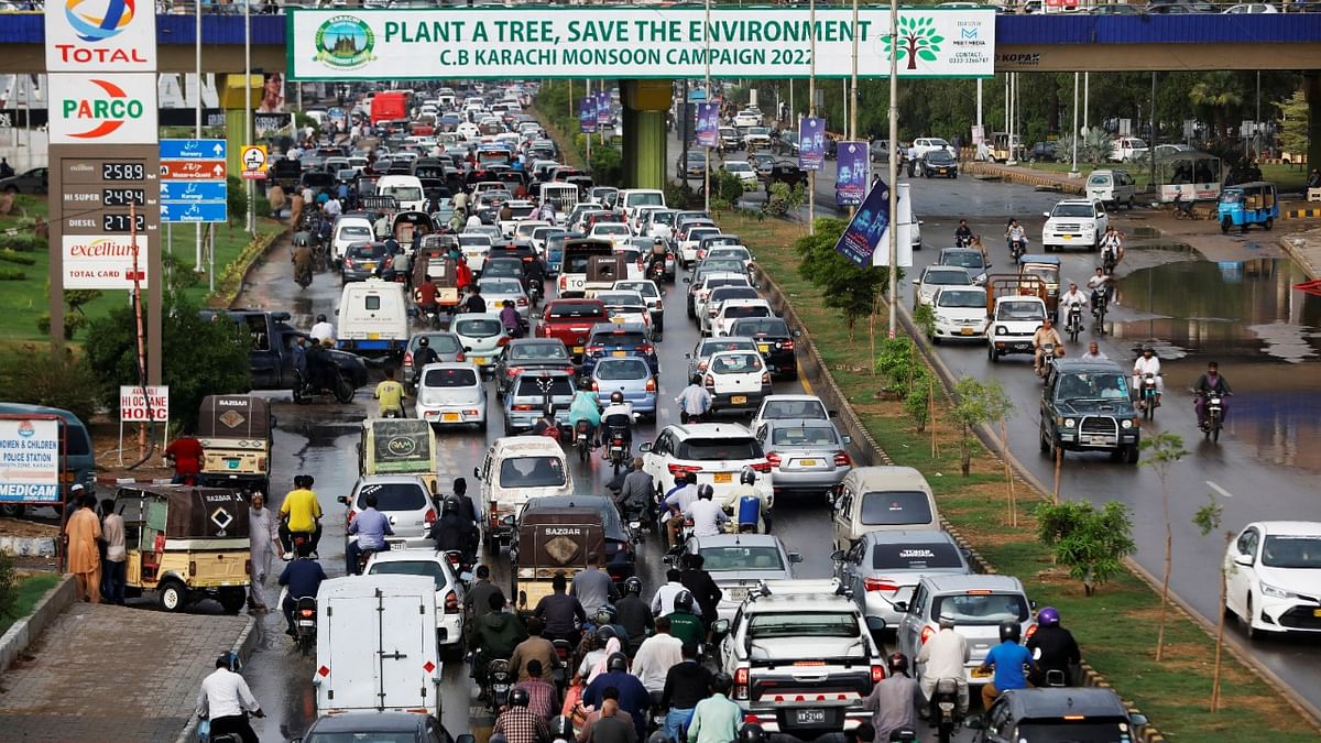 Traffic moves under a bridge displaying a banner from the monsoon tree plantation campaign in Karachi, Pakistan. Credit: Reuters photo