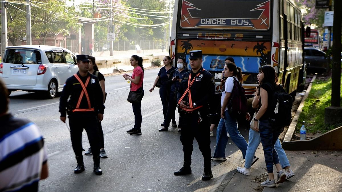 Policemen stand guard next to buses on the side of the road after short, medium and long-distance passenger transport companies started an indefinite strike to demand the government cuts in fuel prices and tolls, on July 27, 2022, in Asuncion. Credit: AFP Photo