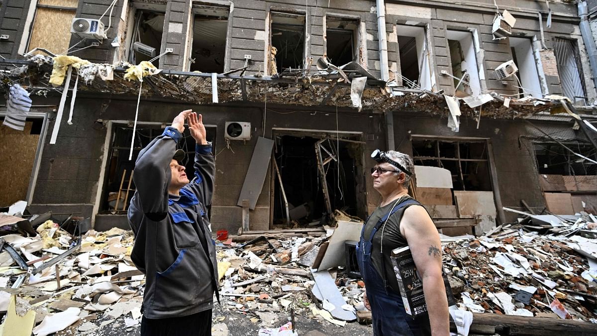 Workers stand in a courtyard amongst debris following an attack on a shopping and office complex in central Kharkiv on July 27, 2022, amid Russian invasion of Ukraine. Credit: AFP Photo